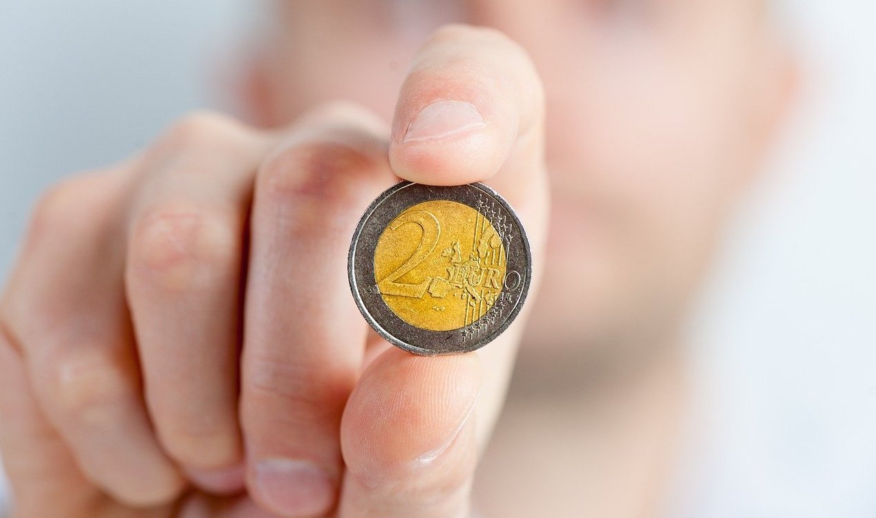 Man holding up a 2 Euro coin.