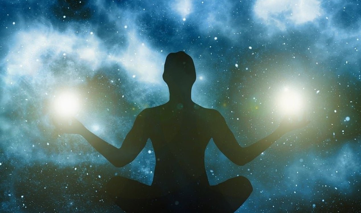 Silhouette of a person meditating with stars in the background.