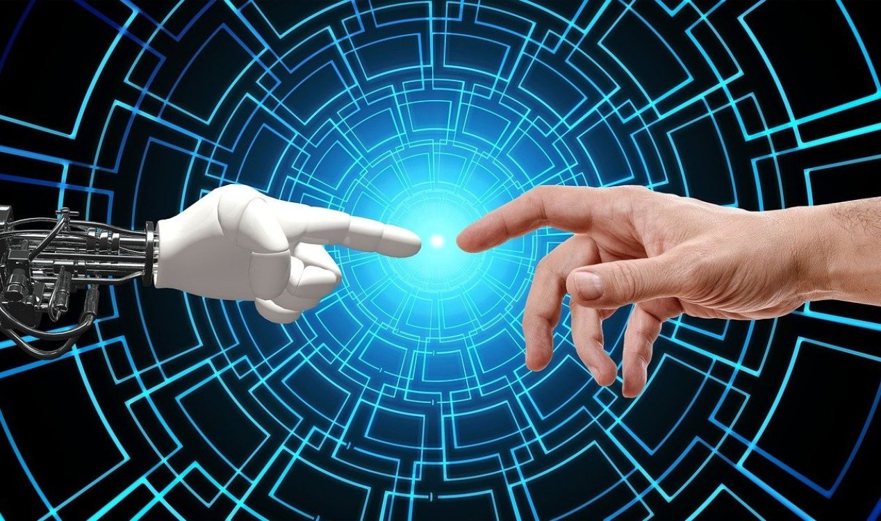 A human hand touching the robotic hand of an artificial intelligence.