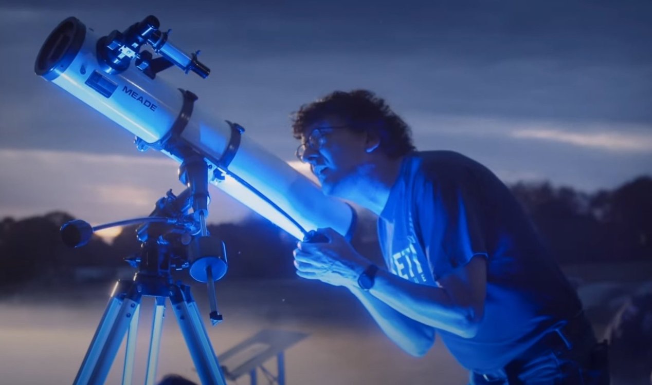An astronomer looks through a telescope.