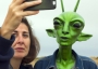 Woman taking a selfie with a green alien.