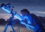 An astronomer looks through a telescope.