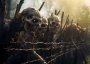 Zombies attempting to break through a barbed wire fence.